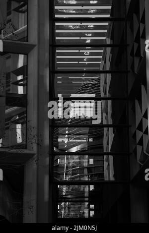 Une photo en niveaux de gris de la silhouette des personnes assises dans un café reflétée sur une fenêtre en verre Banque D'Images