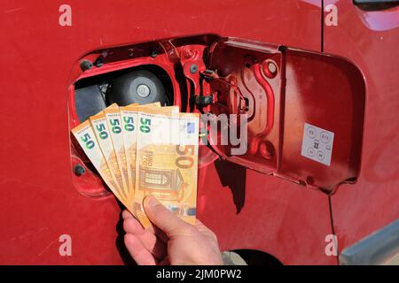Une main tenant un paquet de cinquante billets d'euros en police d'un réservoir de carburant. Banque D'Images