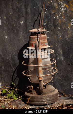 Une vieille lampe d'ouragan rouillée est posée sur une ardoise au soleil. Banque D'Images