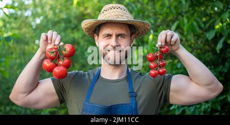 happy man greengrocer dans un chapeau de paille avec un bouquet de tomates Banque D'Images