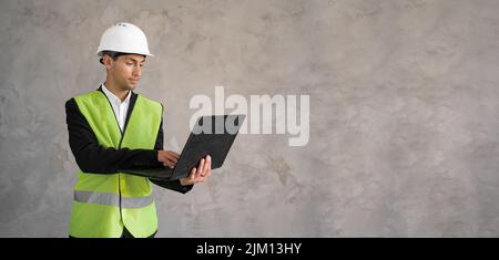 Ingénieur civil musulman utilisant un ordinateur portable. Concept d'ingénierie et de construction. Ingénieur avec ordinateur portable. Homme en casque. Veste d'architecte jaune Banque D'Images