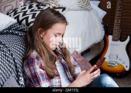 enfant libre fille de loisirs en utilisant le téléphone mobile à la maison Banque D'Images