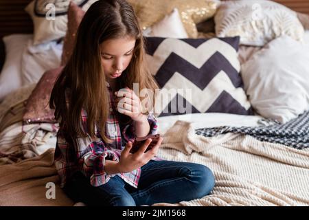 enfant libre fille de loisirs en utilisant le téléphone mobile à la maison Banque D'Images