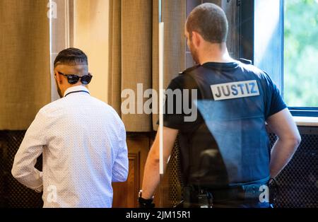 04 août 2022, Bade-Wurtemberg, Tübingen: Le défendeur de 20 ans (l) est dirigé par un fonctionnaire de la Cour dans une salle de la Cour régionale de Tübingen. Le défendeur aurait tué un homme qui était son beau-frère « selon la loi islamique » en novembre 2021 à Mössingen avec trois blessures par coups de couteau au cœur. Photo: Christoph Schmidt/dpa Banque D'Images