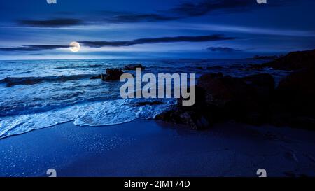 la nuit, il y a d'immenses pierres sur la plage de sable. de merveilleuses vacances de velours sur la mer noire, sous la lumière de la lune. des vagues calmes lavant le rivage. des nuages Banque D'Images