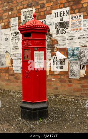 Une boîte postale victorienne avec des affiches d'époque sur le mur derrière à Blists Hill Victorian Village, Ironbridge, Shropshire, Angleterre Banque D'Images