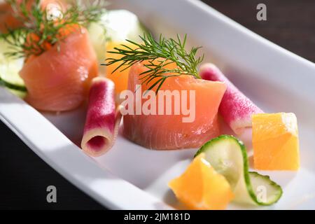 Buffet de tranches de saumon marinées avec radis, concombre et cubes d'orange Banque D'Images