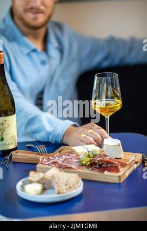 mâle avec verre de vin blanc, charcuterie et plateau de fromages. Banque D'Images