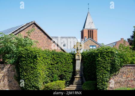 Deutschland, NRW, Kreis Düren, Vettweiß, Wegekreuz au18. JH.Am Marktplatz, dahinter der Turm der katholischen Pfarrkirche Sankt Gereon Banque D'Images