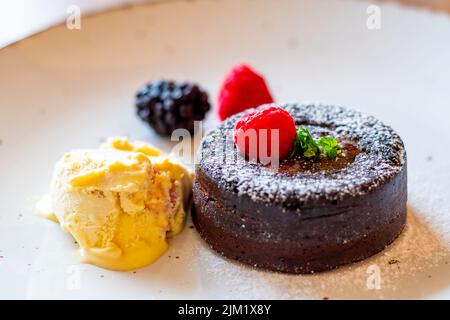 Fondant au chocolat (cupcake) avec framboises, crème glacée et sucre en poudre placés sur l'assiette Banque D'Images