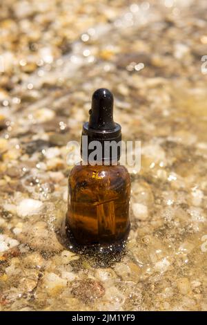 Sérum cosmétique dans une bouteille en verre avec une pipette sur des pierres Banque D'Images