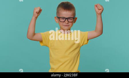 Je suis fort et indépendant. Petit enfant garçon montrant le biceps et regardant confiant, sentir la force de pouvoir pour se battre pour les droits, l'énergie pour gagner la réussite gagner. Enfant d'âge préscolaire sur fond bleu Banque D'Images