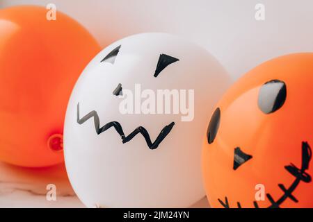 Les jacks peints font face aux ballons. Préparation des boules orange et blanches pour halloween. Activités à la maison pour Halloween. Jouets faits main Banque D'Images