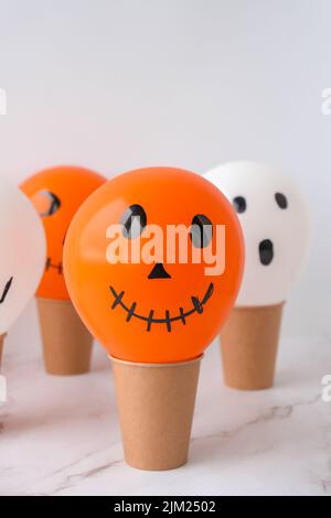 Les jacks peints font face aux ballons. Préparation des boules orange et blanches pour halloween. Activités à la maison pour Halloween. Jouets faits main Banque D'Images