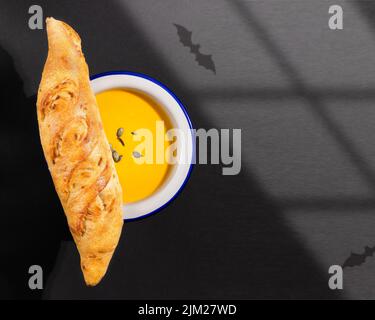 Halloween, composition alimentaire avec purée de potiron maison avec baguette fraîche croquante sur fond noir avec ombres chauves-souris. Mystique, ha Banque D'Images