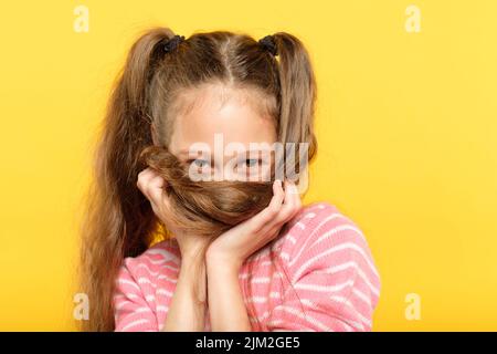 drôle et ludique, insouciante, petite fille, qui se berce les cheveux Banque D'Images