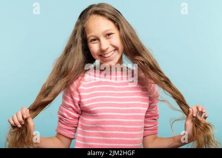 souriant adolescent fille tire queues cheveux sans souci Banque D'Images