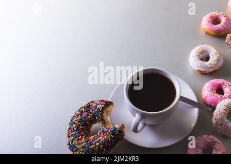 Vue en grand angle du café noir frais dans une tasse au milieu des beignets avec espace de copie sur fond blanc Banque D'Images