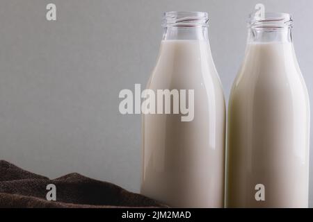 Gros plan du lait dans des bouteilles en verre sur fond gris avec espace de copie Banque D'Images