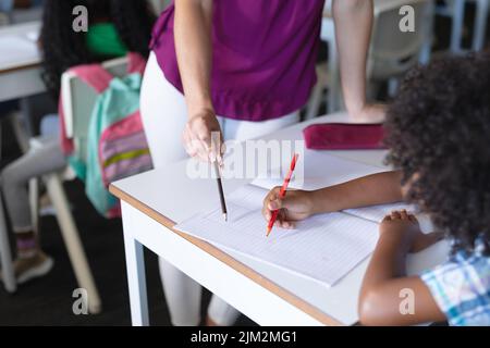 Mi-section de jeunes femmes du caucase enseignant à l'école élémentaire afro-américaine Banque D'Images