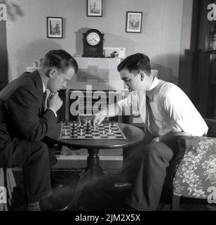 1950s, historique, deux hommes en chemise et cravates, assis à une petite table dans une pièce de devant jouant aux échecs, Angleterre, Royaume-Uni. Banque D'Images