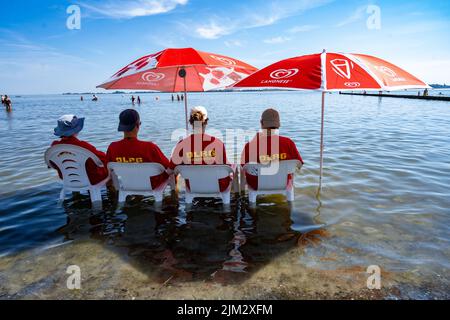 Stralsund, Allemagne. 04th août 2022. Les sauveteurs de la Société allemande de sauvetage (DLRG) s'assoient sur des chaises dans l'eau de refroidissement du lido en cette chaude journée du milieu de l'été, en regardant l'action dans la mer. Credit: Stefan Sauer/dpa/Alay Live News Banque D'Images