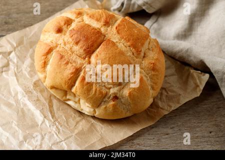 Pain rond de boule fait maison sur papier brun, table rustique en bois. Concept boulangerie Banque D'Images