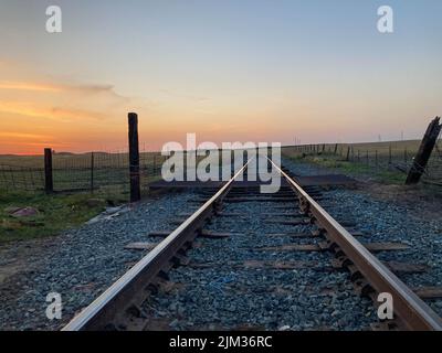 Voies de train menant à un coucher de soleil dans la distance à Oakdale, Californie Banque D'Images