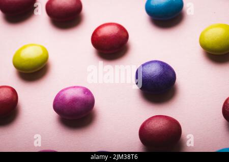 Vue rapprochée en grand angle des bonbons au chocolat multicolores sur fond rose Banque D'Images