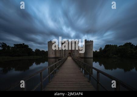 Image longue exposition du château de Bodiam dans East Sussex au coucher du soleil avec le château et les arbres reflétés dans la lande environnante Banque D'Images