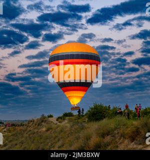 GÖREME/TURQUIE - 30 juin 2022: Montgolfière survole les touristes près des collines de göreme. Banque D'Images