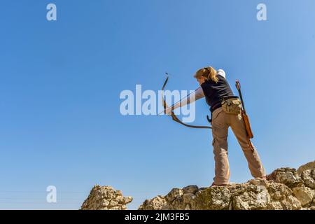 Homme avec arc et flèche pratiquant le tir à l'arc dans le parc. Banque D'Images