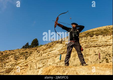 Homme avec arc et flèche pratiquant le tir à l'arc dans le parc. Banque D'Images