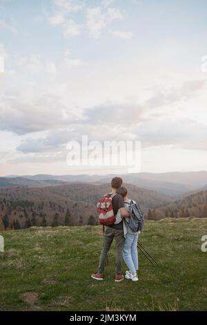 Arrière sur couple debout au sommet de la montagne et appréciant la vue magnifique dans les hugs. Randonneurs. Banque D'Images