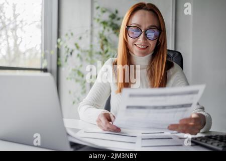 Une femme mûre heureuse avec des documents ou des factures dans un bureau Banque D'Images