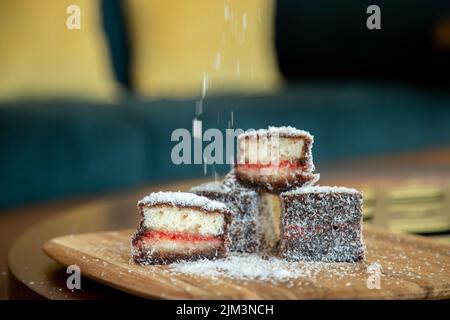 Lamington square cake Australian with coconut on a wooden board with sprinkles with grain and out of focus Stock Photo