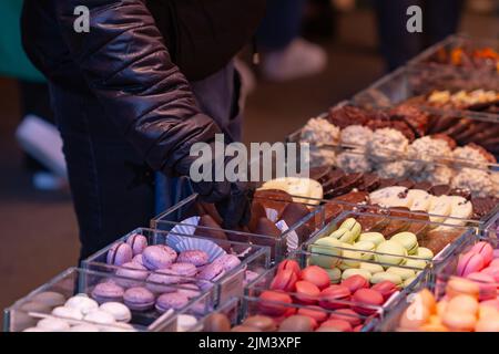 Homme méconnaissable en gant noir prenant un bonbon sur le marché, accent sélectif sur le gant noir. Banque D'Images