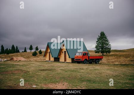 Les deux petits cottages et un camion dans la prairie contre le ciel nuageux. Monténégro. Banque D'Images