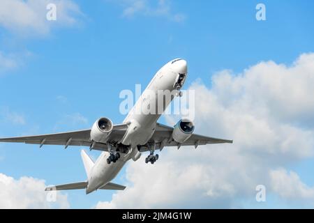 L'avion prend son envol en rétractant le train d'atterrissage sur fond bleu ciel Banque D'Images