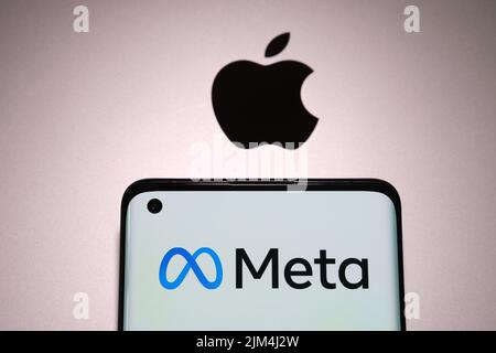 Le logo de la société META est visible sur le smartphone, qui est gravé sur le dessus du macbook avec un logo pomme flou. Concept. Stafford, Royaume-Uni, 31 juillet 2022 Banque D'Images