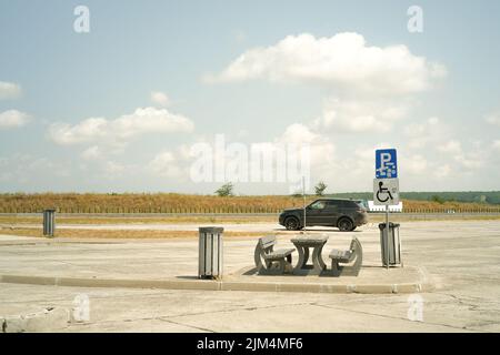 Une gamme Land rover noire s'éloignant d'une station-service et un panneau de signalisation pour les véhicules handicapés Banque D'Images