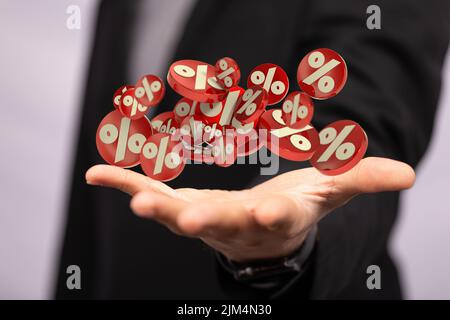 Une main d'homme d'affaires sur un arrière-plan flou en utilisant 3D icônes de pourcentage de ventes de rendu Banque D'Images