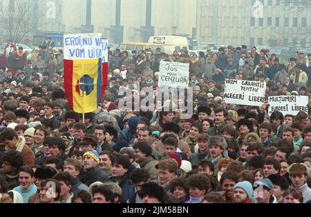 Bucarest, Roumanie, janvier 1990. Rassemblement sur la place de l'Université après la révolution roumaine de 1989. Les gens se rassembleraient tous les jours pour protester contre les anciens dirigeants communistes qui ont pris le pouvoir après la Révolution. Le drapeau roumain avec l'emblème socialiste coupé était un symbole anticommuniste pendant la révolution. Bannières disant « nos héros, nous ne vous oublierons jamais », « la censure est nouvelle », « nous voulons des garanties pour des élections libres », « Merci, radio Free Europe ». Banque D'Images