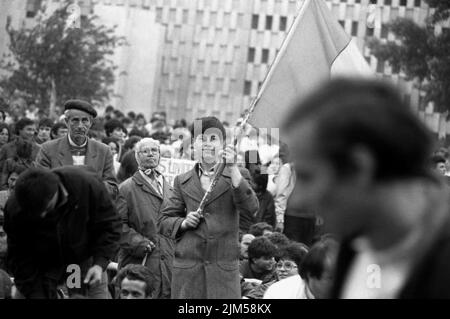 Bucarest, Roumanie, avril 1990. « Golaniada », une importante manifestation anti-communiste sur la place de l'université après la révolution roumaine de 1989. Les gens se rassembleraient tous les jours pour protester contre les ex-communistes qui ont pris le pouvoir après la Révolution. La principale demande était qu'aucun ancien membre du parti ne soit autorisé à se présenter aux élections de 20 mai. Sur cette photo, un garçon agite le drapeau roumain avec l'emblème socialiste coupé, un symbole anticommuniste pendant la révolution. Banque D'Images