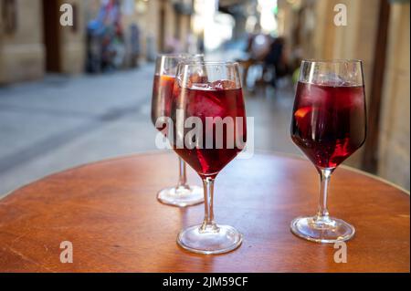 Des verres de vin de sangria froid sont servis en plein air au bar avec vue sur la vieille rue de San Sebastian, pays basque, Espagne en été Banque D'Images