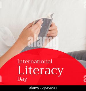 Composite des mains de la femme caucasienne tenant le livre et le texte de la journée internationale d'alphabétisation Banque D'Images
