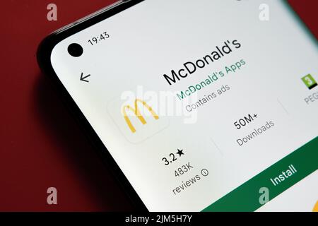 Application McDonald's vue dans Google Play Store sur l'écran du smartphone placé sur fond rouge. Gros plan avec mise au point sélective. Stafford, United King Banque D'Images