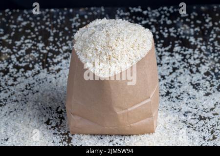 un tas de riz blanc dans un sac de papier et sur la table Banque D'Images