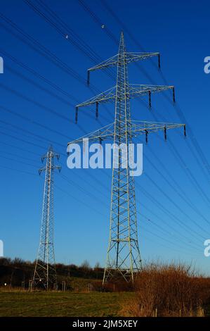 Pylônes haute tension à côté de l'autoroute A5 à Francfort-Riedberg, en Allemagne, contre le ciel bleu du soir. Banque D'Images