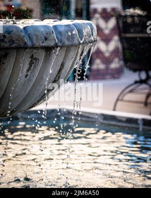 Un gros plan vertical des gouttes d'eau s'écoulant de la piscine de la fontaine ornementale Banque D'Images